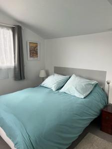 a bedroom with a large bed with blue sheets and pillows at La petite campagne in Blaru