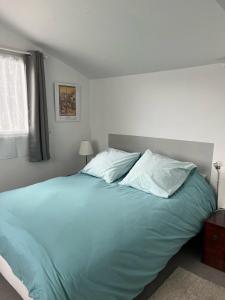 una camera da letto con un grande letto con lenzuola e cuscini blu di La petite campagne a Blaru
