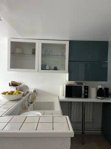 a kitchen with white cabinets and a microwave at La petite campagne in Blaru
