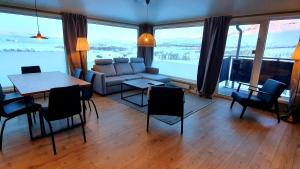 Katterjåkk Apartments في Riksgränsen: غرفة معيشة مع أريكة وطاولة وكراسي