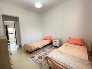 Cette chambre comprend 3 lits et un tapis. dans l'établissement Spacious Cozy Appartment Akid Lotfi ORAN, à Oran