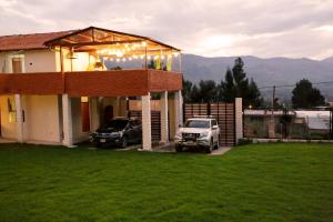 a house with two cars parked in front of it at Finca Ramos Mejia in Coporaque