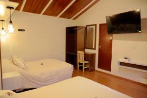 a hotel room with two beds and a flat screen tv at Finca Ramos Mejia in Coporaque
