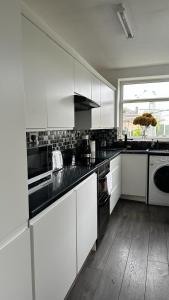 a kitchen with white cabinets and black counter tops at Ur Place 204 in Manchester