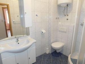 La salle de bains blanche est pourvue d'un lavabo et de toilettes. dans l'établissement Tolle Ferienwohnung in Privlaka mit Terrasse, Grill und Garten, à Privlaka