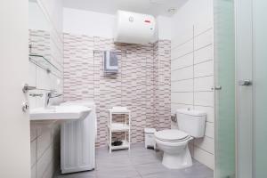 a white bathroom with a toilet and a sink at City Life Marina apartment No. 15 in Ampavris