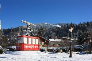 a red train car in the snow next to a street light at Cabana & L Altima Megeve Service in Megève
