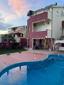 a resort with a swimming pool in front of a building at Apartments Villa Stella Maris in Rogoznica