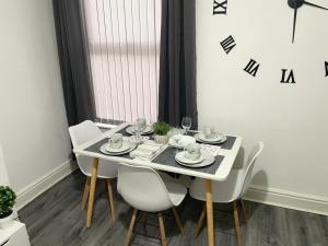 a dining room table with chairs and a table and a clock at Cosy Spacious Family & Contractor Friendly 3 Bedroom House Near Liverpool Centre Sleeps 6 in Liverpool