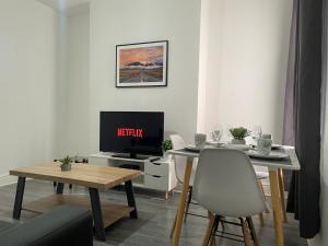 a living room with a table and a television at Cosy Spacious Family & Contractor Friendly 3 Bedroom House Near Liverpool Centre Sleeps 6 in Liverpool