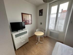 1 dormitorio con TV, mesa y silla en Hôtel de Nantes, en La Bernerie-en-Retz