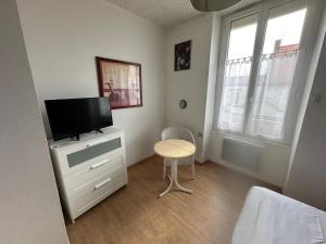 a bedroom with a tv and a table and a chair at Hôtel de Nantes in La Bernerie-en-Retz