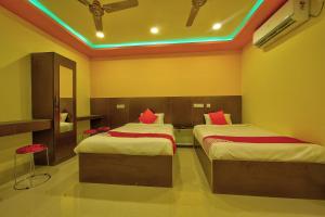 um quarto com 2 camas e almofadas vermelhas em Collection O Joliday Inn em Mahabalipuram