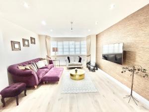 ein Wohnzimmer mit einem lila Sofa und einem TV in der Unterkunft Stonegrove Luxury House London Free Off Street Parking And EVC Port in Stone Grove