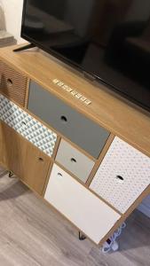 une télévision au-dessus d'une armoire en bois avec des tiroirs dans l'établissement Studio Toulouse -Croix Daurade, à Toulouse