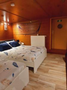 two beds in a bedroom with wooden walls at Gîte Le Sambre in Thuin
