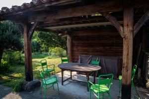 Chambre d'Hôtes et gites du Tapissier في Polignac: طاولة وكراسي خشبية تحت بروجولا خشبي