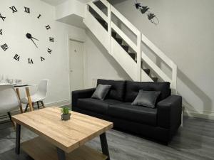 a living room with a black couch and a clock at Cosy Spacious Family & Contractor Friendly 3 Bedroom House Near Liverpool Centre Sleeps 6 in Liverpool