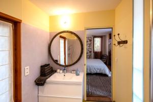 uma casa de banho com um lavatório, um espelho e uma cama em Chambre d'Hôtes et gites du Tapissier em Polignac