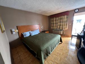 Schlafzimmer mit einem Bett mit grüner Tagesdecke in der Unterkunft Lone Star Inn & Suites in Harlingen