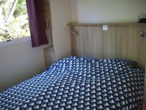 Un dormitorio con una cama azul y blanca y una ventana en Belles vacances aux chalets en Casteljaloux