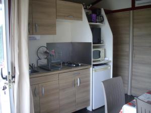 a small kitchen with wooden cabinets and a sink at Belles vacances aux chalets Casteljaloux in Casteljaloux