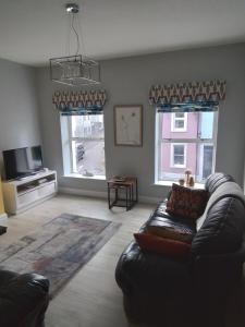 a living room with a leather couch and two windows at John & Mary's in Dromore