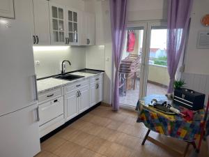 a kitchen with white cabinets and a sink and a table at Apartments Villa Stella Maris in Rogoznica