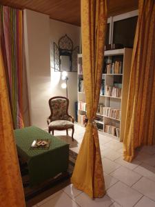 a living room with curtains and a chair and a book shelf at La Demeure in Gabarret