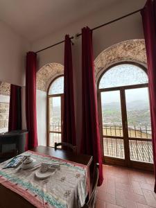 a bedroom with a bed and two large windows at B&B PALAZZO SASSATELLI in Cascia