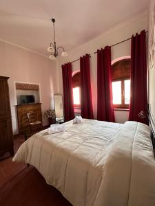 una camera da letto con un grande letto bianco con tende rosse di B&B PALAZZO SASSATELLI a Cascia
