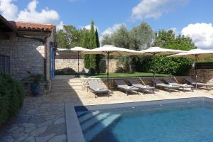 a swimming pool with lounge chairs and umbrellas at Villa Emma Smoljanci 76 in Svetvinčenat