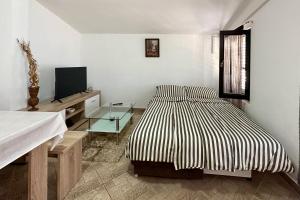 ein weißes Schlafzimmer mit einem Bett und einem TV in der Unterkunft Pahert Beach Apartment in Vir