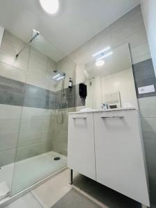 ein weißes Bad mit einer Dusche und einem Waschbecken in der Unterkunft Cosy Appartement Montferrand tout équipé 6prs 27 Languedoc in Clermont-Ferrand