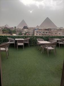 eine Gruppe von Tischen und Stühlen auf einem Balkon mit Pyramiden in der Unterkunft Fantastic three pyramids view in Kairo