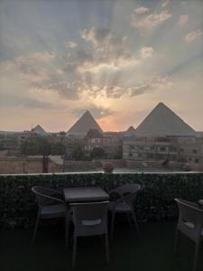 Fantastic three pyramids view في القاهرة: طاولة وكراسي مع الاهرامات في الخلفية