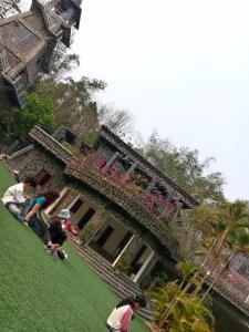 a group of people sitting on the grass in front of a building at Khu nghỉ dưỡng GOOD TIME in Ban Hin Lom