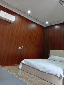 Un dormitorio con una pared de madera y una cama en Khu nghỉ dưỡng GOOD TIME en Bản Him Lom