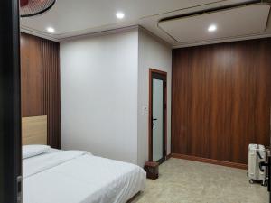 1 dormitorio con cama blanca y pared de madera en Khu nghỉ dưỡng GOOD TIME en Bản Him Lom