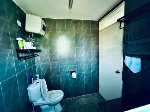 a bathroom with a toilet and a green tiled wall at Malixa Lofts in Wakiso