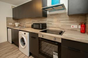 a kitchen with a stove top oven next to a washing machine at Merchant City Apartment in Glasgow