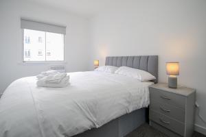 a bedroom with a large white bed and a window at Merchant City Apartment in Glasgow