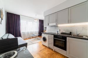 a kitchen with white cabinets and a living room at Fox studio apartment in Šiauliai