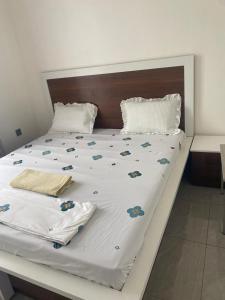 uma cama grande com lençóis brancos e flores em The Pyramid Apart em Kigali