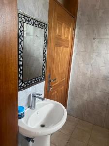 baño con lavabo, espejo y puerta en The Pyramid Apart en Kigali