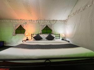 a bedroom with a large bed with two lamps at The Himalayan Cottage Camping With Bonfire, Manali - Riverside in Manāli