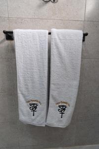 twee witte handdoeken hangend aan een handdoekenrek in de badkamer bij Tuya Pyramids Inn hotel in Caïro