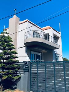 ein weißes Haus mit einem Zaun davor in der Unterkunft Keskos Luxury Villa in Artemida