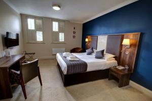 a bedroom with a bed with a desk and a blue wall at The Rochford Hotel in Southend-on-Sea +13 photos