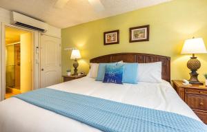 1 dormitorio con 1 cama blanca grande con almohadas azules en Kamaole Sands 6-207 condo, en Wailea